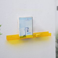 a yellow shelf with two pictures on it and a potted plant in the background