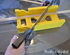 a person holding a knife over a yellow object on top of a glass table with sticks sticking out of it