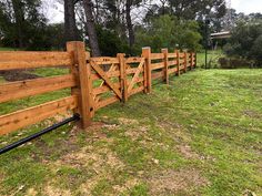 a wooden fence in the middle of a grassy field