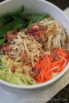 a white bowl filled with veggies and meats on top of a table