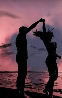 two people are dancing on the beach at sunset