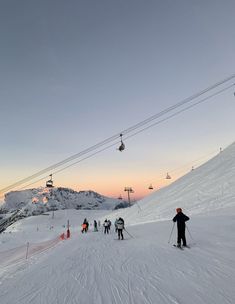 skiers and snowboarders at the bottom of a ski slope with lift in background