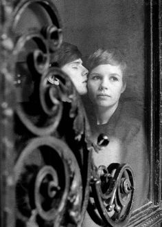 an old black and white photo of two people looking at each other through a mirror