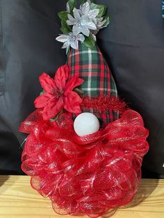 a red mesh wreath sitting on top of a wooden table