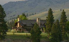 a large log house sitting on top of a lush green hillside