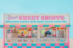 a pink and blue candy shop sitting on top of a sandy beach