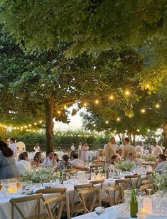 a group of people sitting at tables under trees