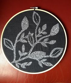 a black and white embroidery on a red leather surface, with leaves in the center