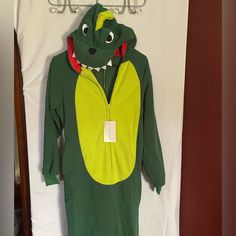 a green dinosaur onesuit hanging on a wall