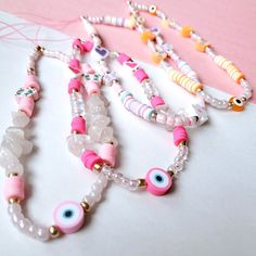 three necklaces with beads and evil eyes on them sitting on top of a table