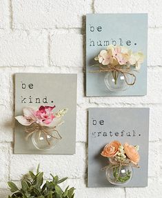 three small vases with flowers are hanging on the wall next to two signs that say be kind and be grateful