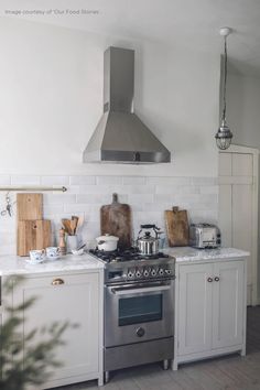 a stove top oven sitting inside of a kitchen next to a counter with cutting boards on it