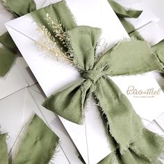 a bow tied on top of an envelope with some green ribbon around the front and side