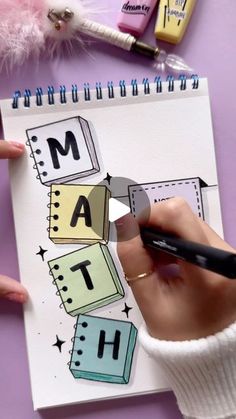 a person is drawing letters on a notepad