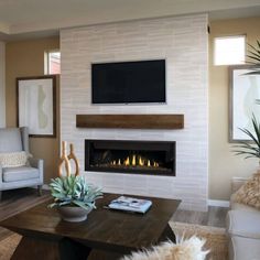 a living room with couches, chairs and a television mounted on the wall in front of a fireplace