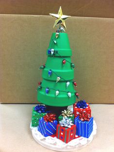 a green christmas tree sitting on top of a white plate next to a cardboard box