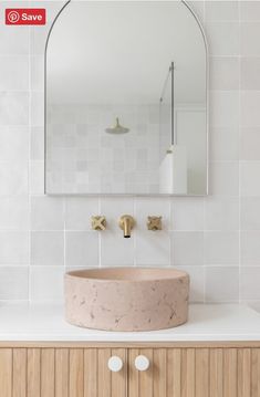 a bathroom sink sitting under a mirror next to a wooden cabinet with two faucets