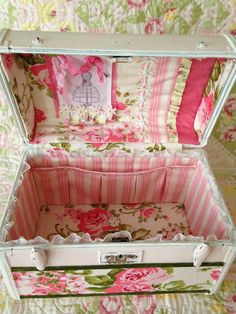 an open suitcase sitting on top of a bed covered in pink and green floral fabric