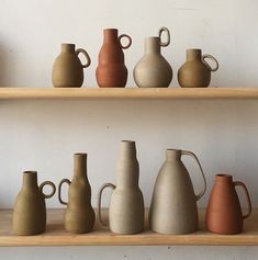 many different vases are lined up on the shelves