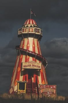 a large red and white striped tower on top of a hill under a cloudy sky