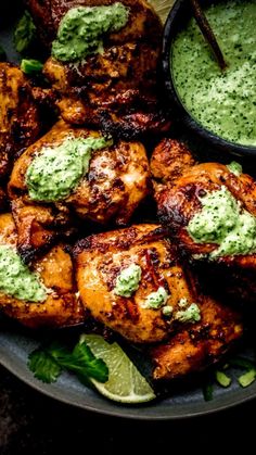 grilled chicken with green sauce and garnishes on a plate, ready to be eaten