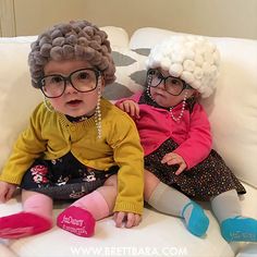 two small children sitting on a couch wearing wigs and eyeglasses for halloween