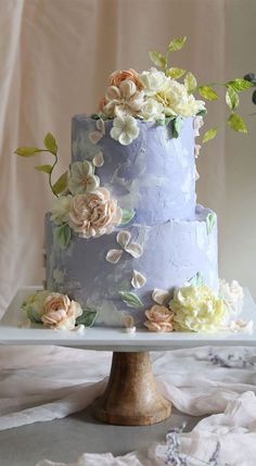 a three tiered blue cake with flowers on top