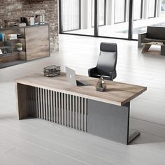 an office desk with a laptop on it in front of a brick wall and large windows