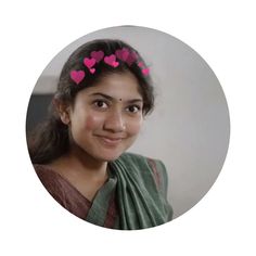 a woman with pink hearts on her head and in a green sari, smiling at the camera