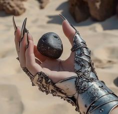 a person holding two rocks in their hands on the sand and rocks are behind them