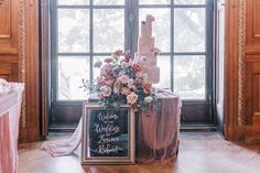 a wedding cake sitting on top of a table next to a window