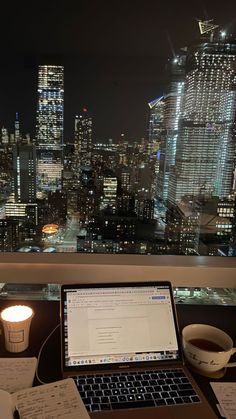 an open laptop computer sitting on top of a desk next to a cup of coffee