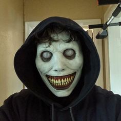 a man in a black hoodie is wearing a creepy mask