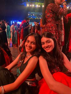 two young women sitting on the floor in front of a crowd at a dance event