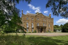 an old brick building with lots of windows on the front and side of it, surrounded by trees