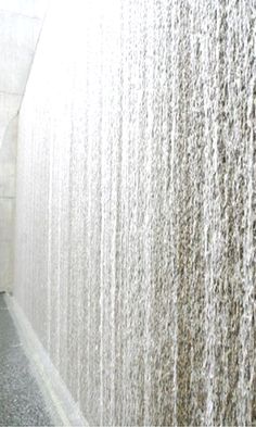 a man standing in front of a wall with water pouring down it's sides