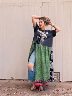 a woman standing in front of a white wall wearing a black shirt and green skirt