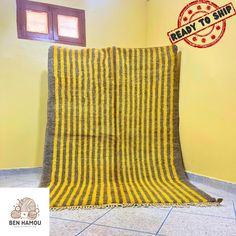 a yellow and grey blanket sitting on top of a tiled floor next to a window