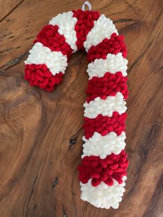 a red, white and blue knitted candy cane ornament on a wooden surface