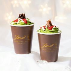 two chocolate cups with green frosting and toppings on top, sitting side by side