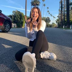 a woman sitting on the ground with her fingers up