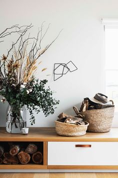 two baskets with plants in them sit on a shelf next to a window and other items