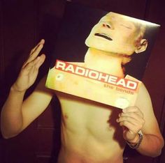 a shirtless man holding up a cardboard box with the words radiohead on it