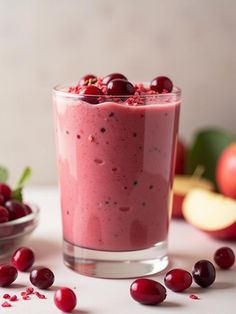 a smoothie with cherries on the side in a glass next to some fruit