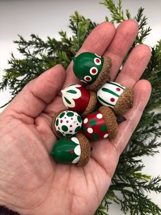 a hand is holding five small chocolates in it's palm, with green and red designs on them