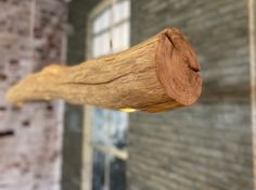 a piece of wood that is hanging from a hook on a brick wall next to a window