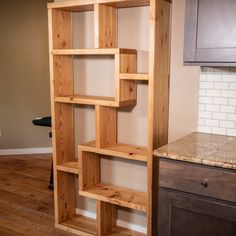 a wooden book shelf sitting on top of a hard wood floor next to a kitchen counter