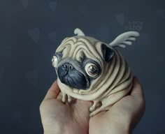 a small pug dog with angel wings on it's head is being held by someone