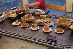 a table topped with lots of different types of sushi and other foods on plates