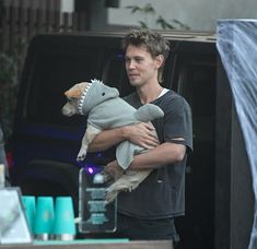 a man holding a stuffed animal in his arms while standing next to a van with the door open